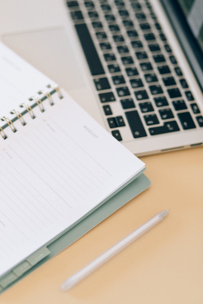 about-us Open notebook next to a laptop and pen on a desk, ideal for business and planning.
